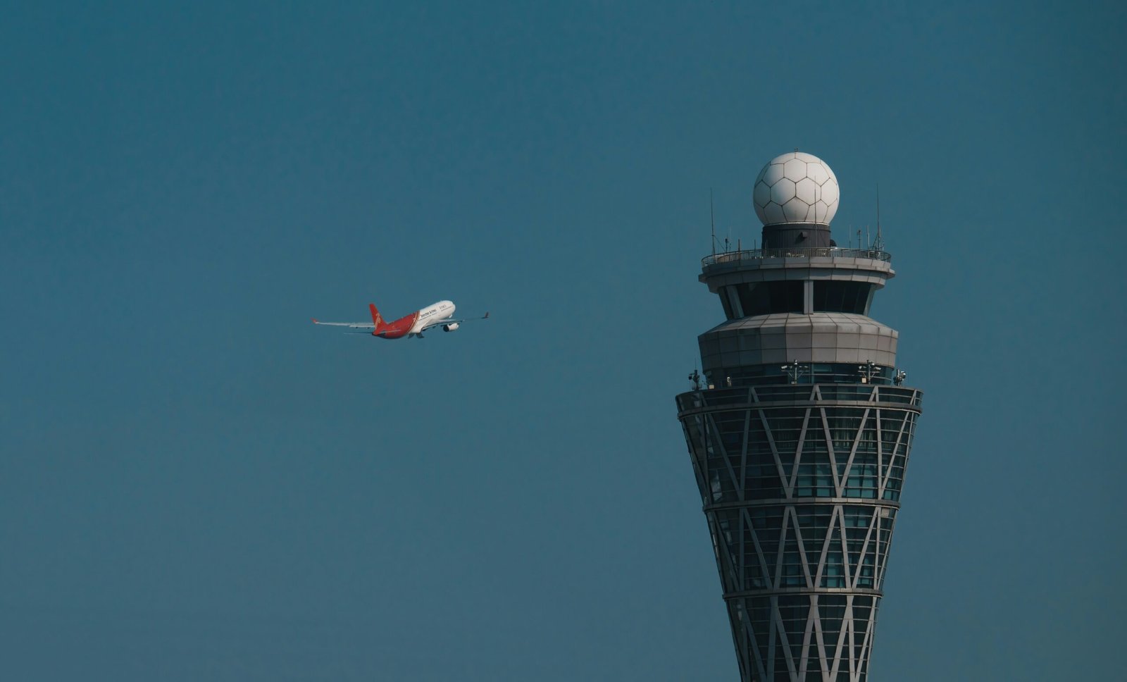 Passenger aircraft taking off beside an airport control tower.