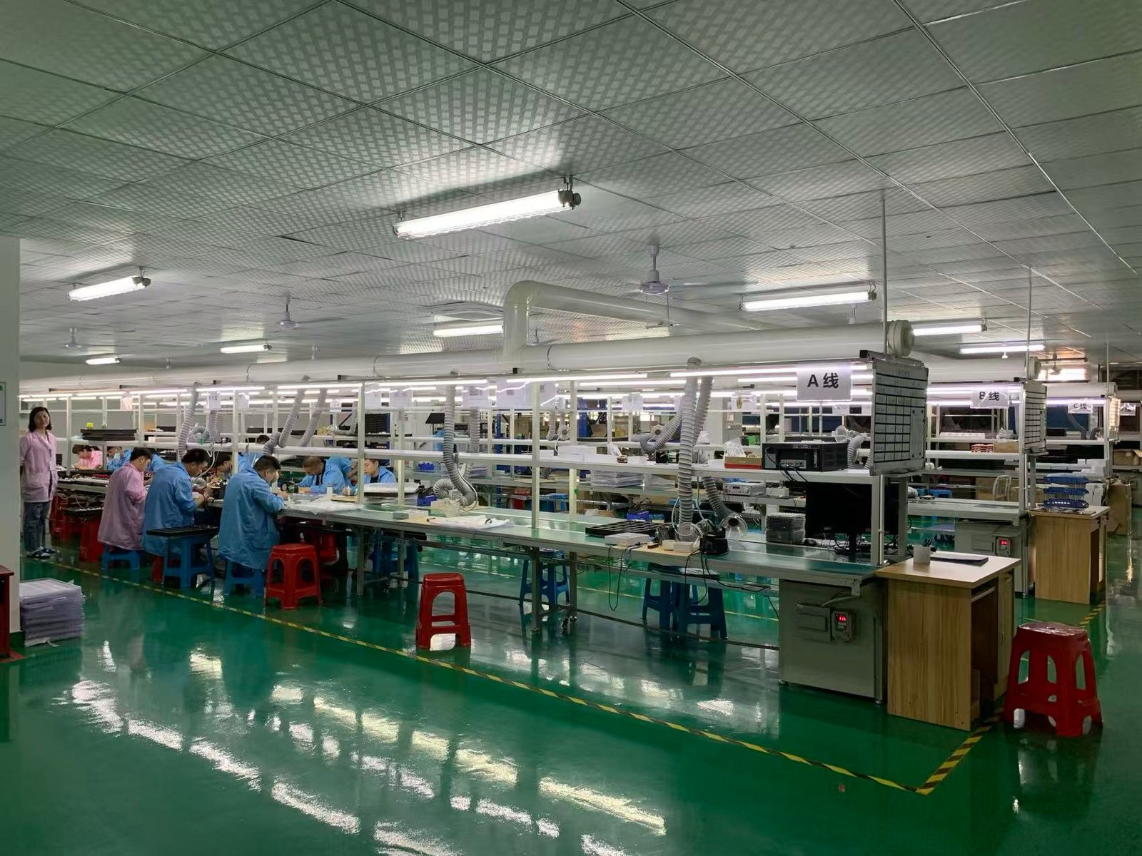 Workers at assembly workstations inside a supplier factory.
